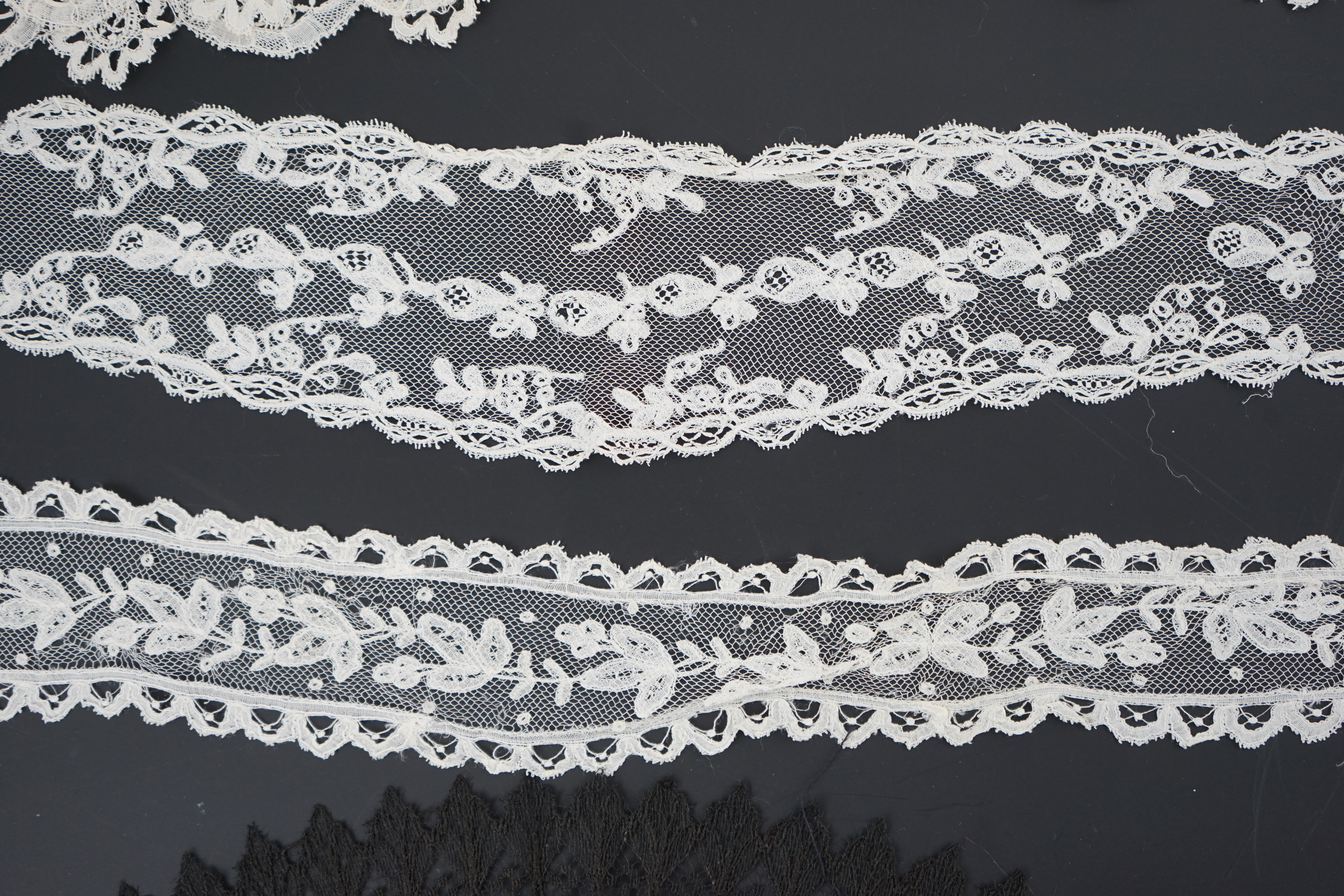 A small collection of late 19th century laces including a cream Brussels bobbin lace collar appliquéd on to net and two similar Brussels bobbin lace lappets, a pair of cream Honiton bobbin lace cuffs and a black lace fal